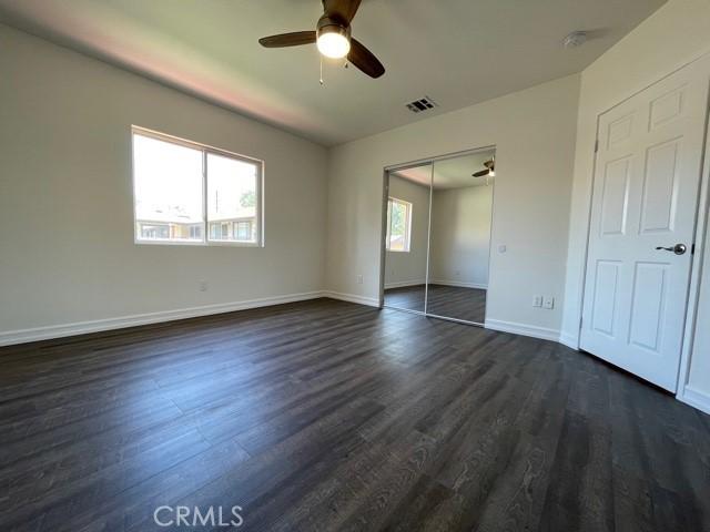 unfurnished bedroom with visible vents, dark wood-type flooring, a ceiling fan, a closet, and baseboards