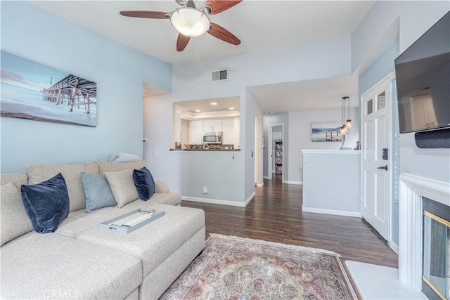 living area featuring a ceiling fan, baseboards, visible vents, and wood finished floors