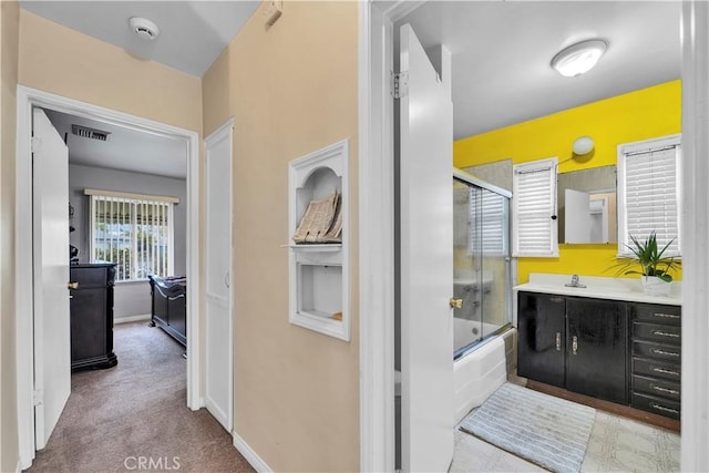 full bathroom with visible vents, vanity, baseboards, and shower / bath combination with glass door