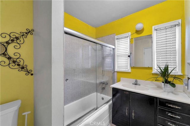 full bath featuring enclosed tub / shower combo, toilet, and vanity