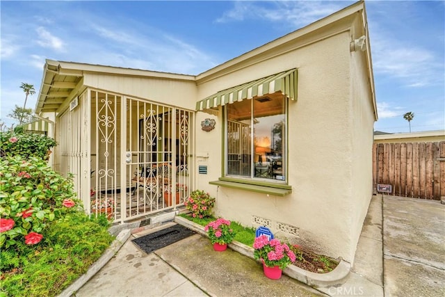 entrance to property with crawl space, stucco siding, a patio, and fence