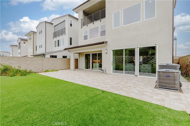 back of property with fence, central AC unit, stucco siding, a yard, and a patio area