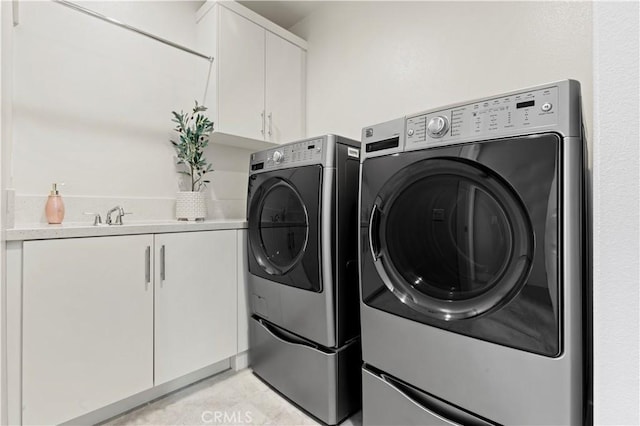 washroom with washer and clothes dryer, cabinet space, light tile patterned flooring, and a sink