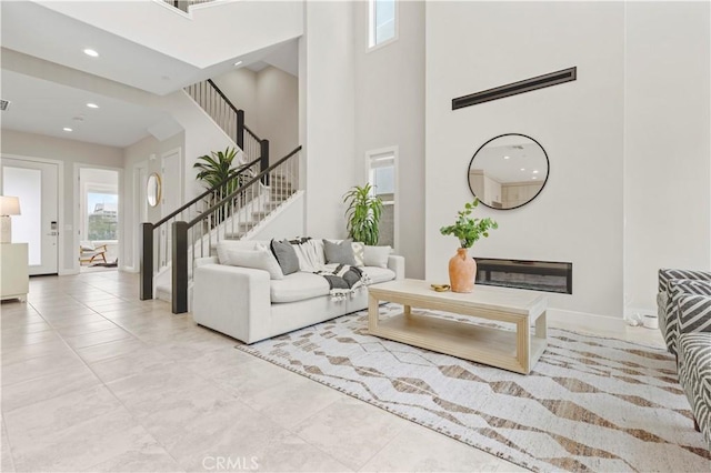 living room with stairway, recessed lighting, a high ceiling, and baseboards