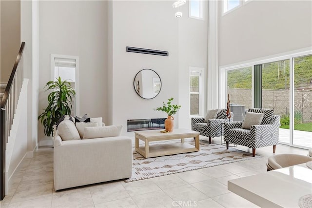 living area with a high ceiling, light tile patterned flooring, and stairs