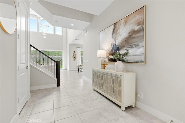 hall featuring visible vents, baseboards, light tile patterned flooring, and stairs