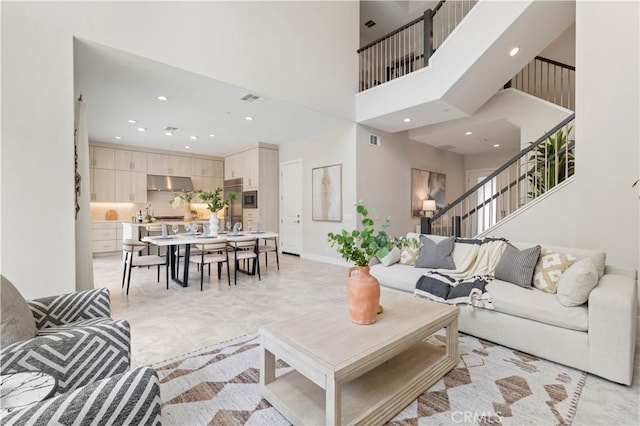 living room featuring visible vents, recessed lighting, stairway, baseboards, and a towering ceiling