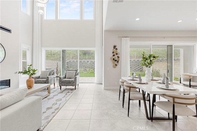 living area with a wealth of natural light, recessed lighting, a towering ceiling, and light tile patterned flooring