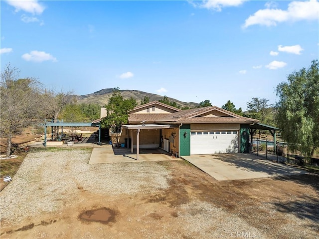 view of front of home featuring a mountain view, a garage, concrete driveway, and fence