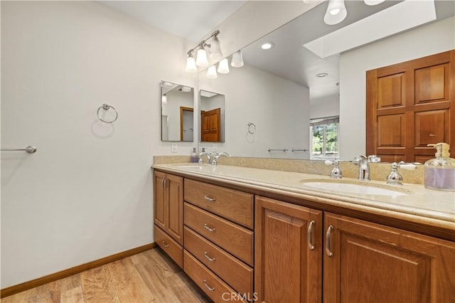 bathroom with a sink, baseboards, wood finished floors, and double vanity