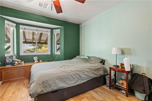 bedroom with a ceiling fan, visible vents, and light wood finished floors