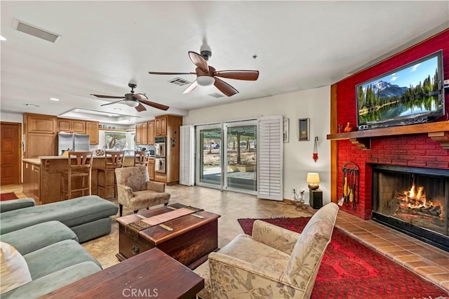 living room featuring a ceiling fan, a fireplace, and visible vents