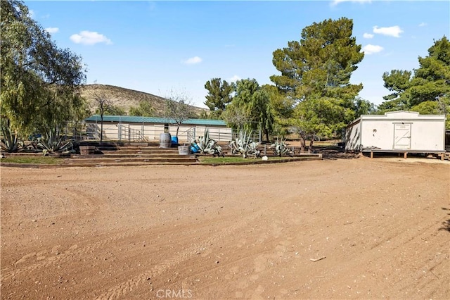 view of yard featuring an outbuilding, a mountain view, and a storage unit