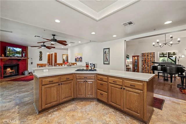 kitchen with visible vents, a brick fireplace, brown cabinetry, and light countertops