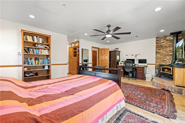 bedroom featuring a wood stove, recessed lighting, wood finished floors, and visible vents