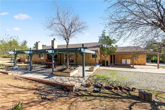 back of property with stucco siding, a chimney, a pergola, and a patio area