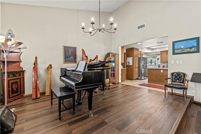 living area featuring visible vents, wood finished floors, baseboards, and a chandelier