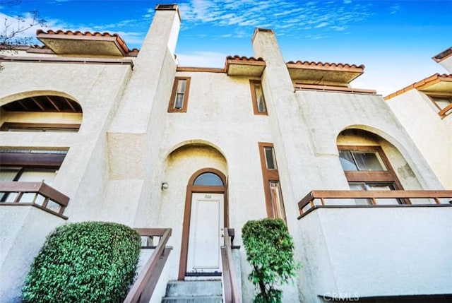 view of front of home with stucco siding and a chimney