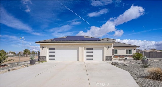 prairie-style house with an attached garage, stucco siding, concrete driveway, stone siding, and roof mounted solar panels