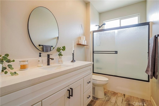 bathroom with toilet, shower / bath combination with glass door, vanity, and wood finished floors