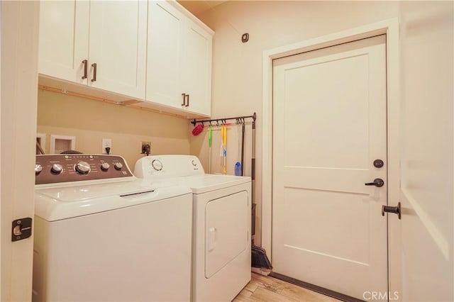 laundry room with cabinet space, washer and dryer, and light wood-style flooring