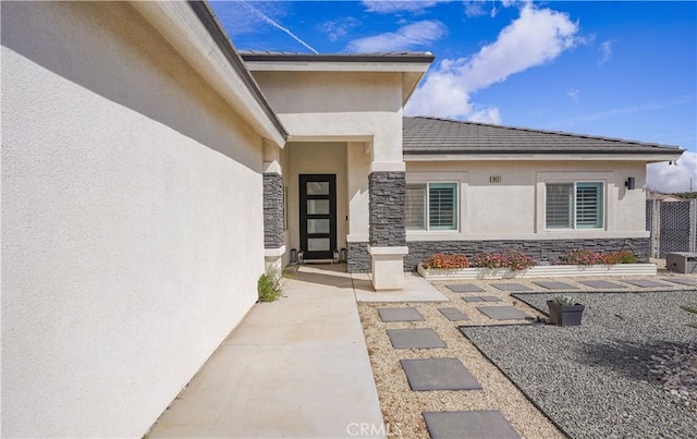 property entrance featuring stone siding and stucco siding