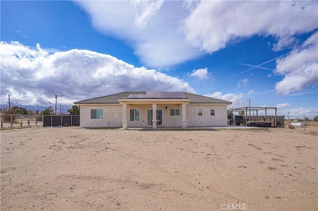 back of property with a patio, fence, roof mounted solar panels, and stucco siding