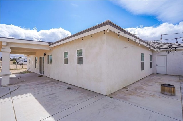 view of side of home with stucco siding and a patio