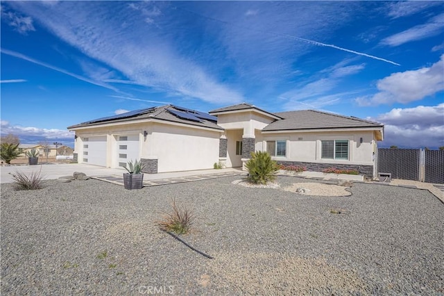 prairie-style home featuring stucco siding, stone siding, concrete driveway, a garage, and solar panels