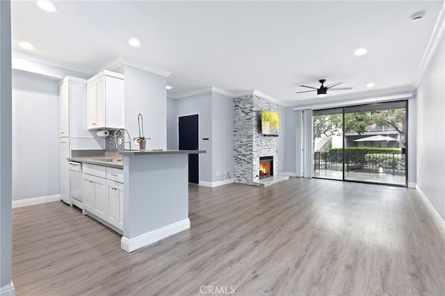 kitchen with baseboards, light wood-type flooring, white dishwasher, white cabinets, and open floor plan