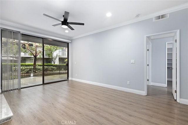 empty room featuring ceiling fan, wood finished floors, visible vents, and ornamental molding