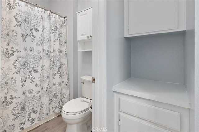 bathroom featuring curtained shower, toilet, and wood finished floors