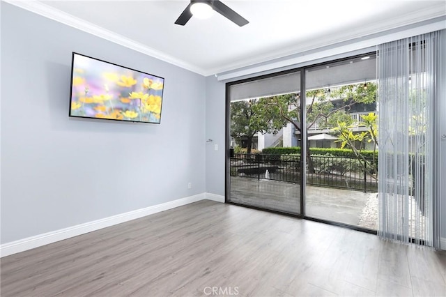 empty room featuring crown molding, wood finished floors, baseboards, and ceiling fan