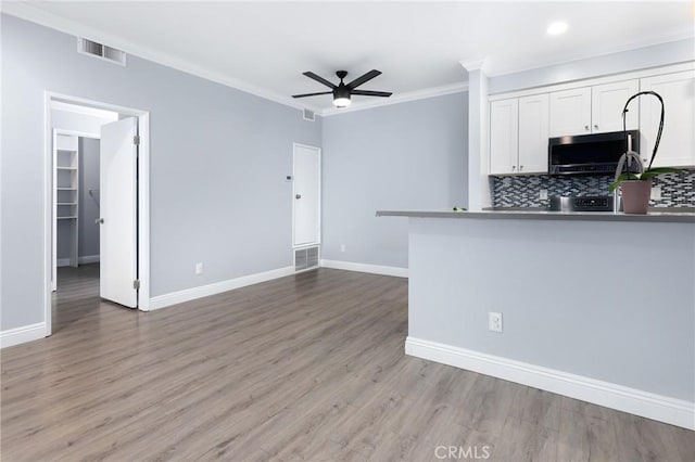 kitchen featuring white cabinets, ornamental molding, visible vents, and ceiling fan