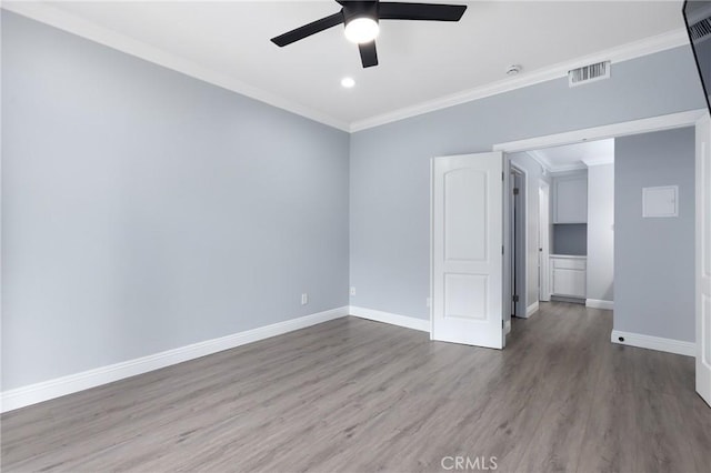 empty room featuring wood finished floors, a ceiling fan, visible vents, baseboards, and ornamental molding