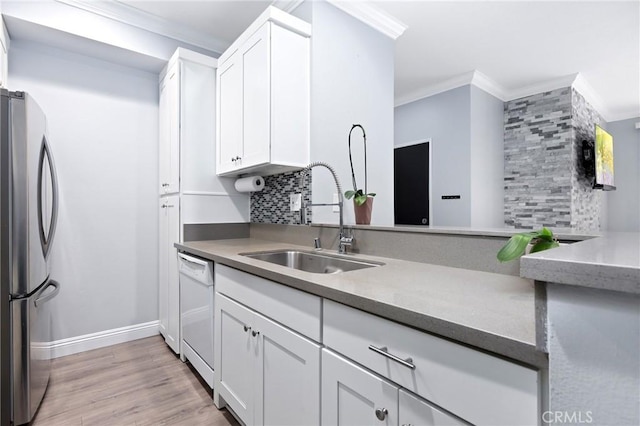 kitchen with tasteful backsplash, ornamental molding, freestanding refrigerator, white dishwasher, and a sink