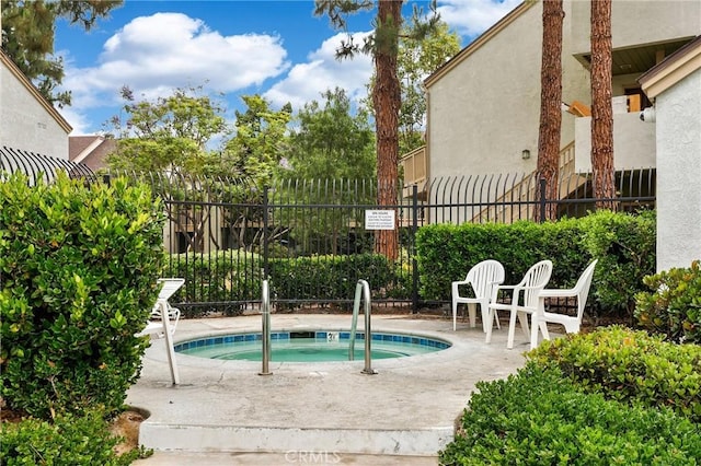 view of swimming pool featuring a patio, fence, and a hot tub