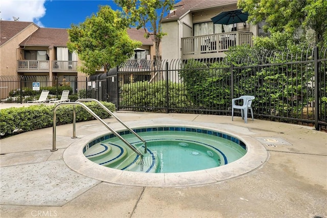 view of swimming pool with fence and a hot tub