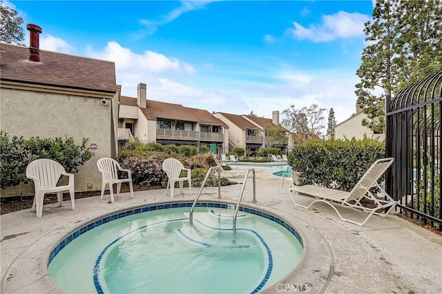 pool with a residential view, a patio, and a hot tub