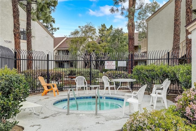 view of swimming pool featuring a community hot tub and fence