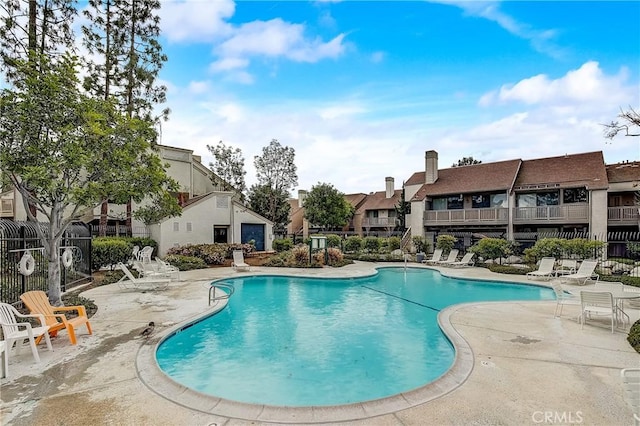 community pool with a residential view, a patio, and fence