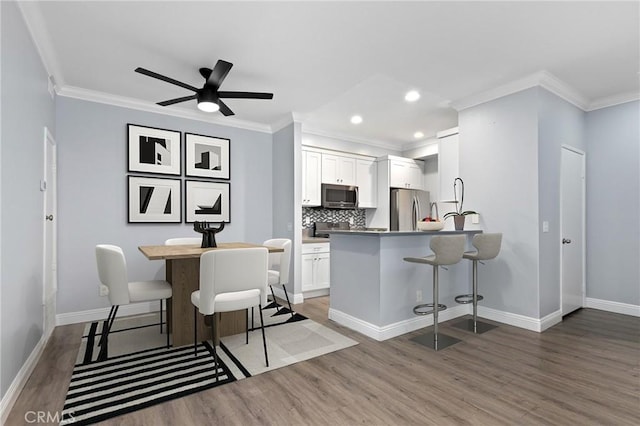 kitchen featuring a kitchen breakfast bar, appliances with stainless steel finishes, white cabinets, and light wood finished floors