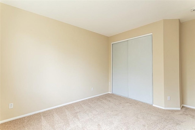 unfurnished bedroom with carpet flooring, baseboards, and a closet