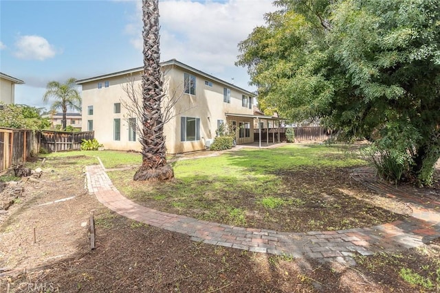 rear view of house featuring stucco siding, a yard, and a fenced backyard