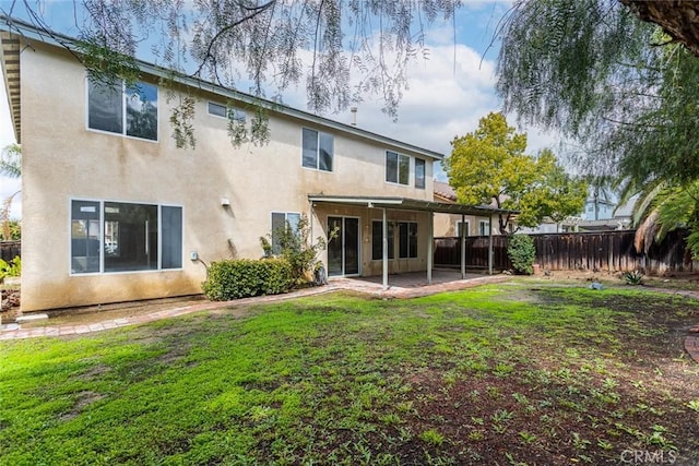 rear view of property featuring stucco siding, a patio, a lawn, and a fenced backyard