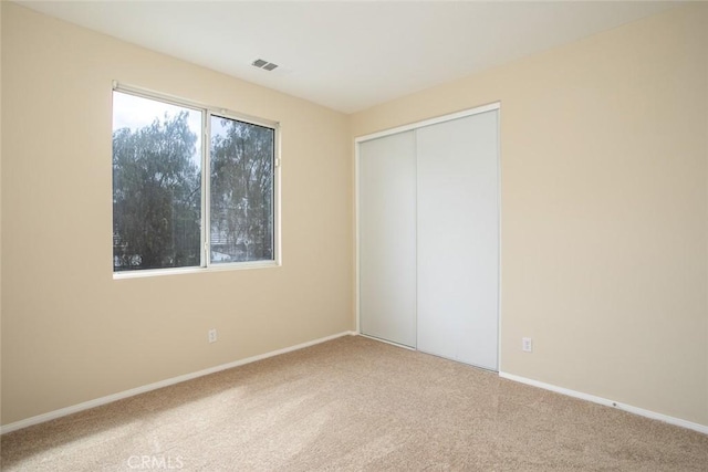 unfurnished bedroom with a closet, visible vents, baseboards, and carpet floors