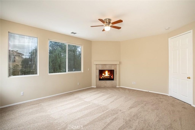 unfurnished living room featuring visible vents, a ceiling fan, carpet, baseboards, and a tile fireplace