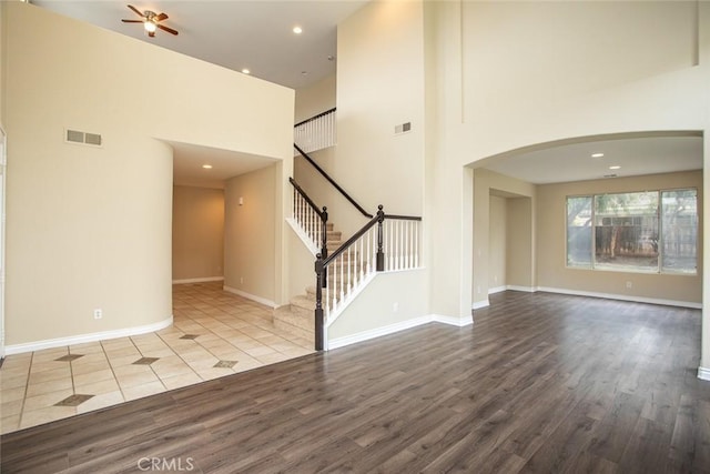 interior space featuring arched walkways, visible vents, ceiling fan, and wood finished floors