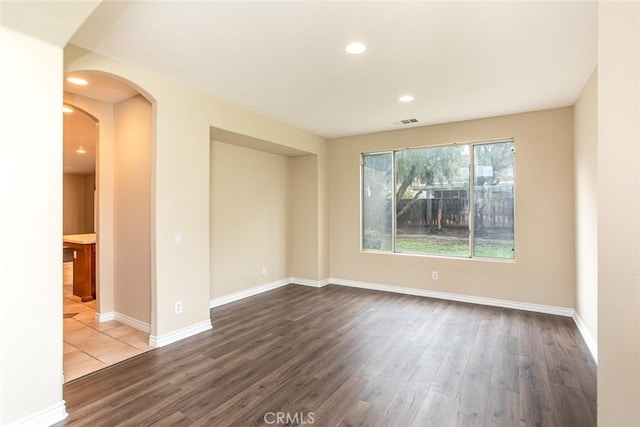 spare room with recessed lighting, baseboards, arched walkways, and wood finished floors