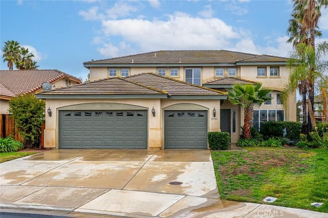 view of front facade featuring stucco siding, a tiled roof, concrete driveway, and a garage